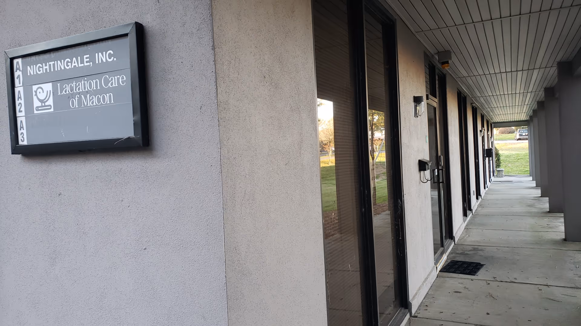 Exterior corridor of a senior care facility with glass doors along a covered walkway.