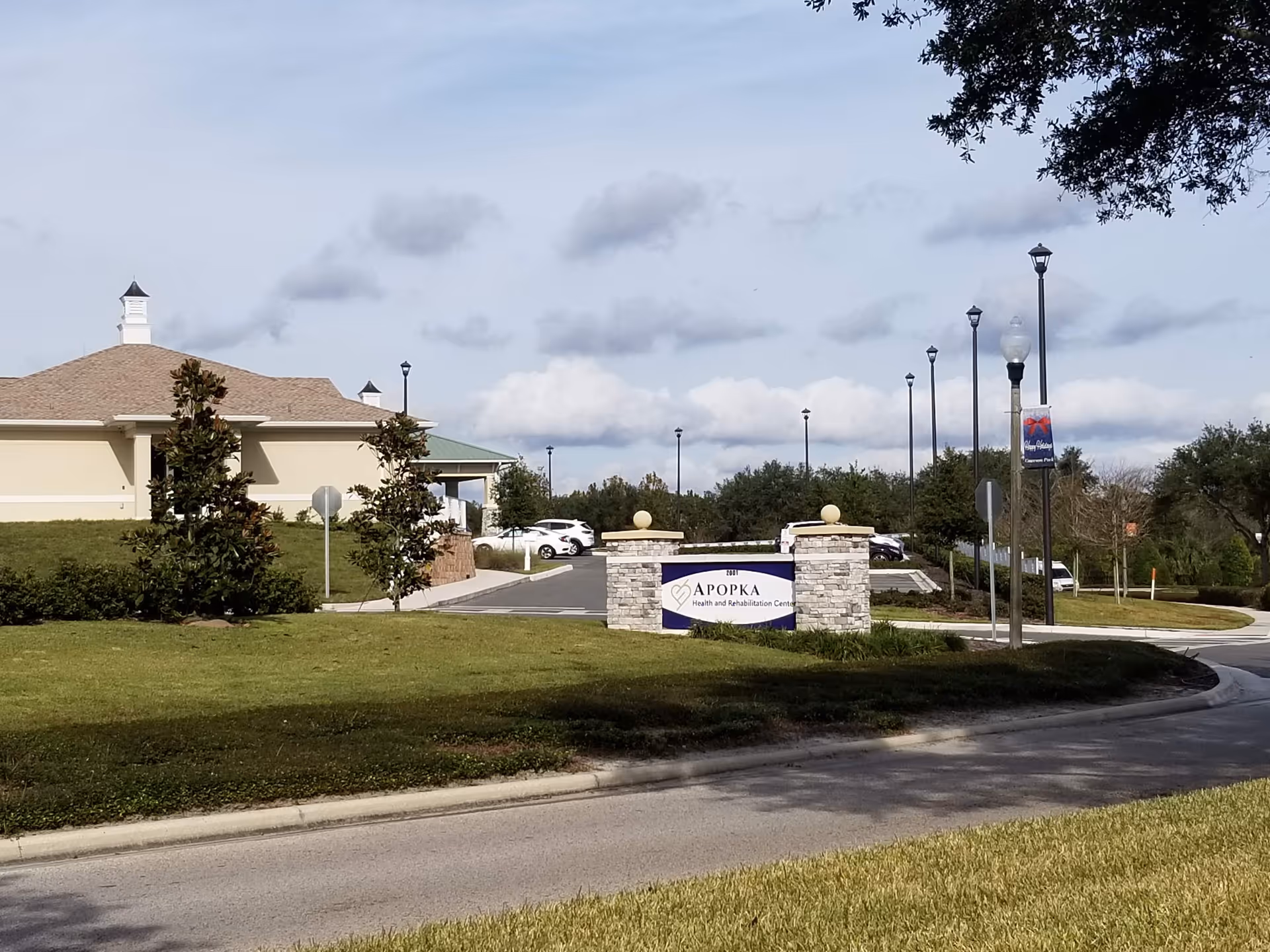 Exterior view of Apopka Health and Rehabilitation Center entrance, sign, and surrounding landscaping.
