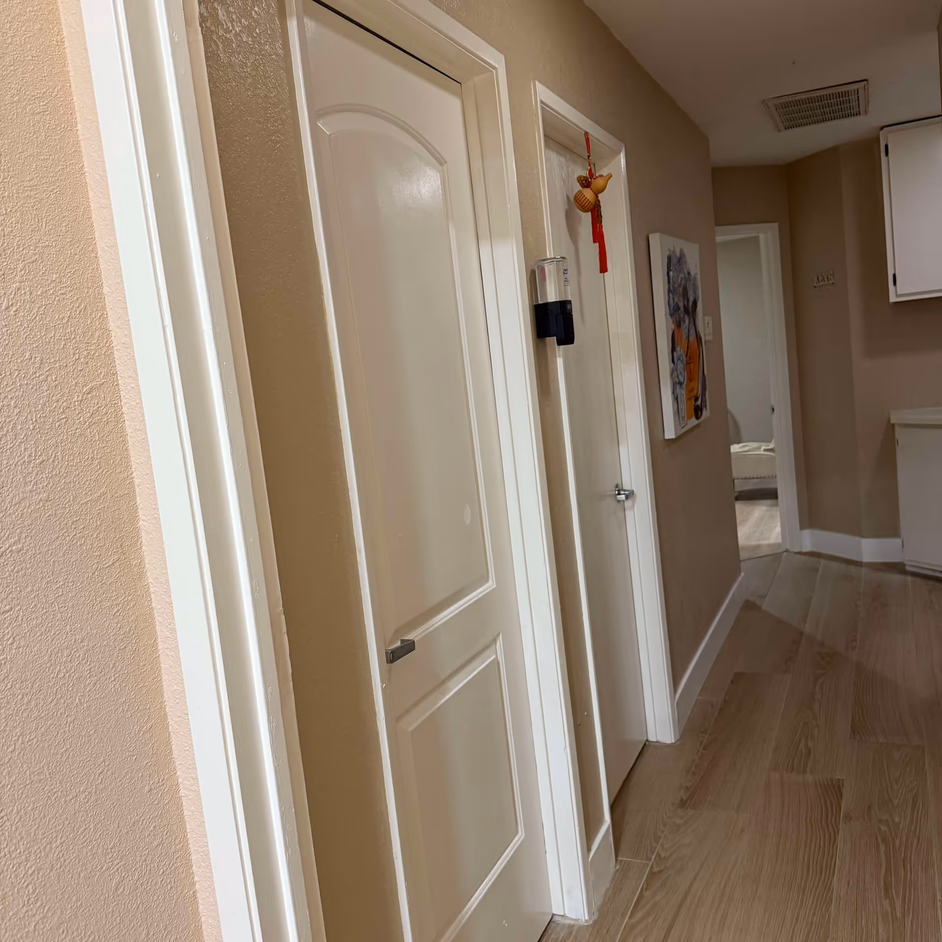 Narrow hallway inside a senior living facility with white doors and beige walls.
