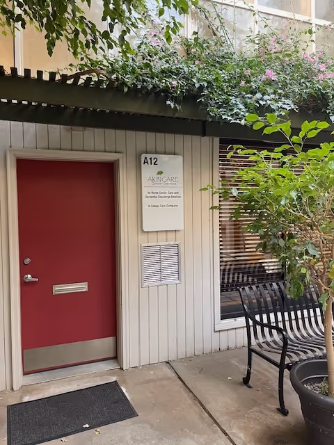 Exterior view of Akin Care Senior Services entrance with a red door and bench.