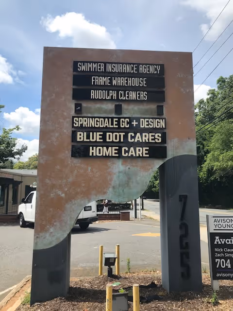 A tall exterior sign for Blue Dot Cares in a parking lot.