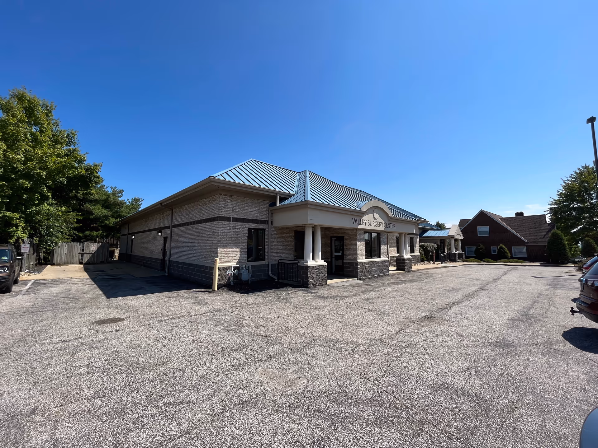Single-story brick building labeled Valley Surgery Center with a parking lot and clear blue sky.