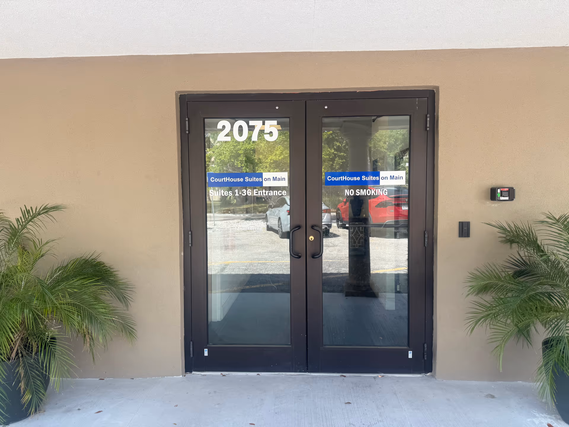 Exterior entrance with double doors, address 2075, and potted palms on both sides.