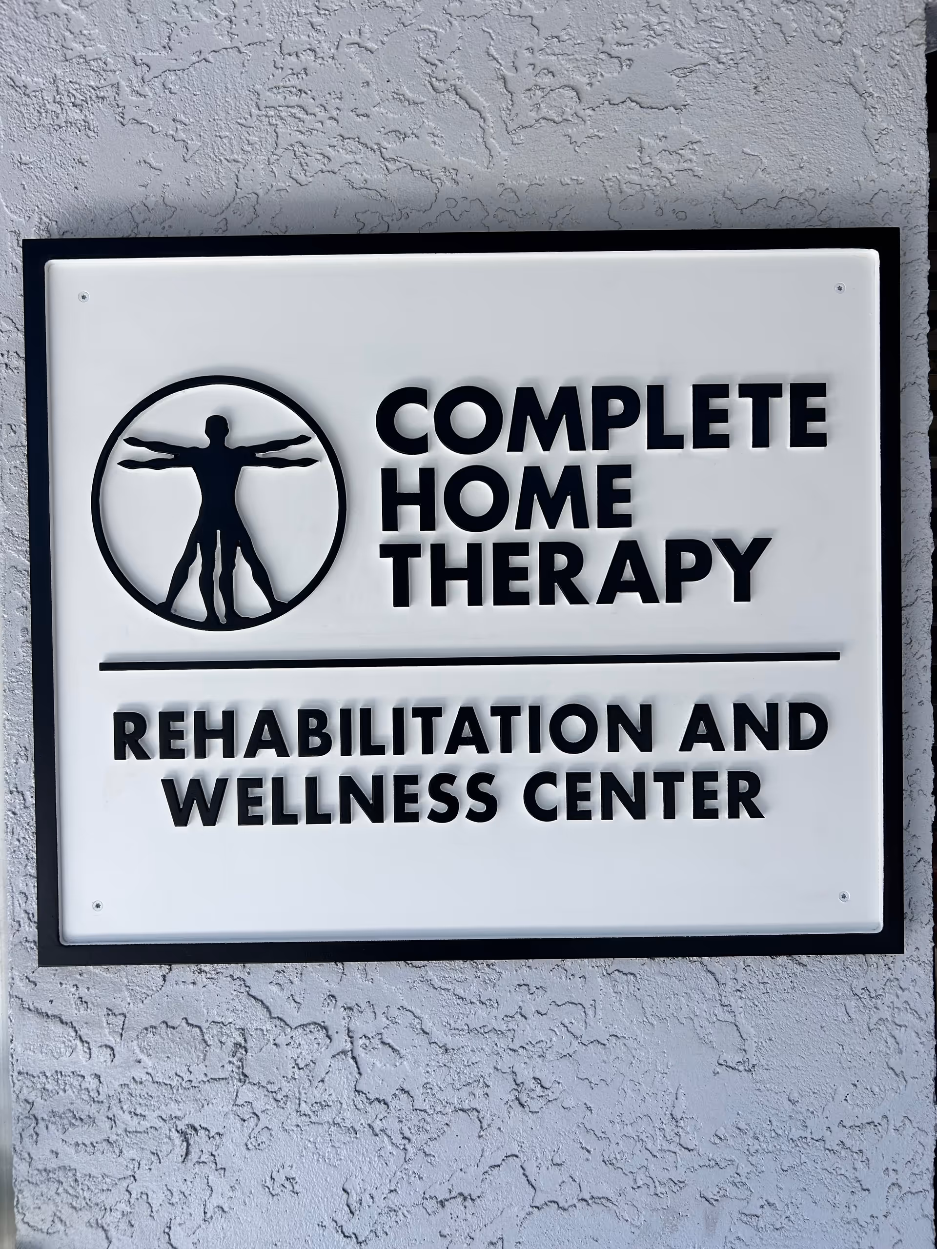Outdoor building sign reading 'Complete Home Therapy' with logo on textured wall.