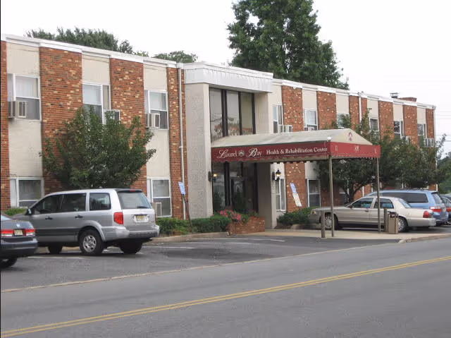 Brick two-story Laurel Bay Health and Rehabilitation Center exterior with red canopy entrance and parked cars.
