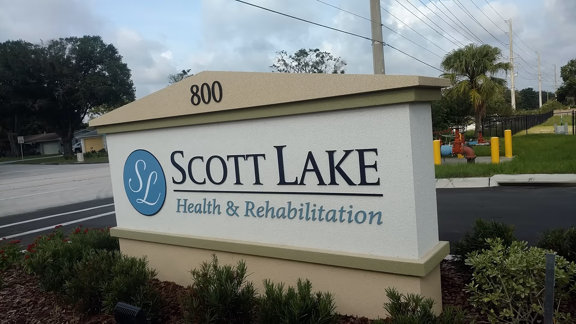 Exterior sign for Scott Lake Health & Rehabilitation with landscaping and road nearby.
