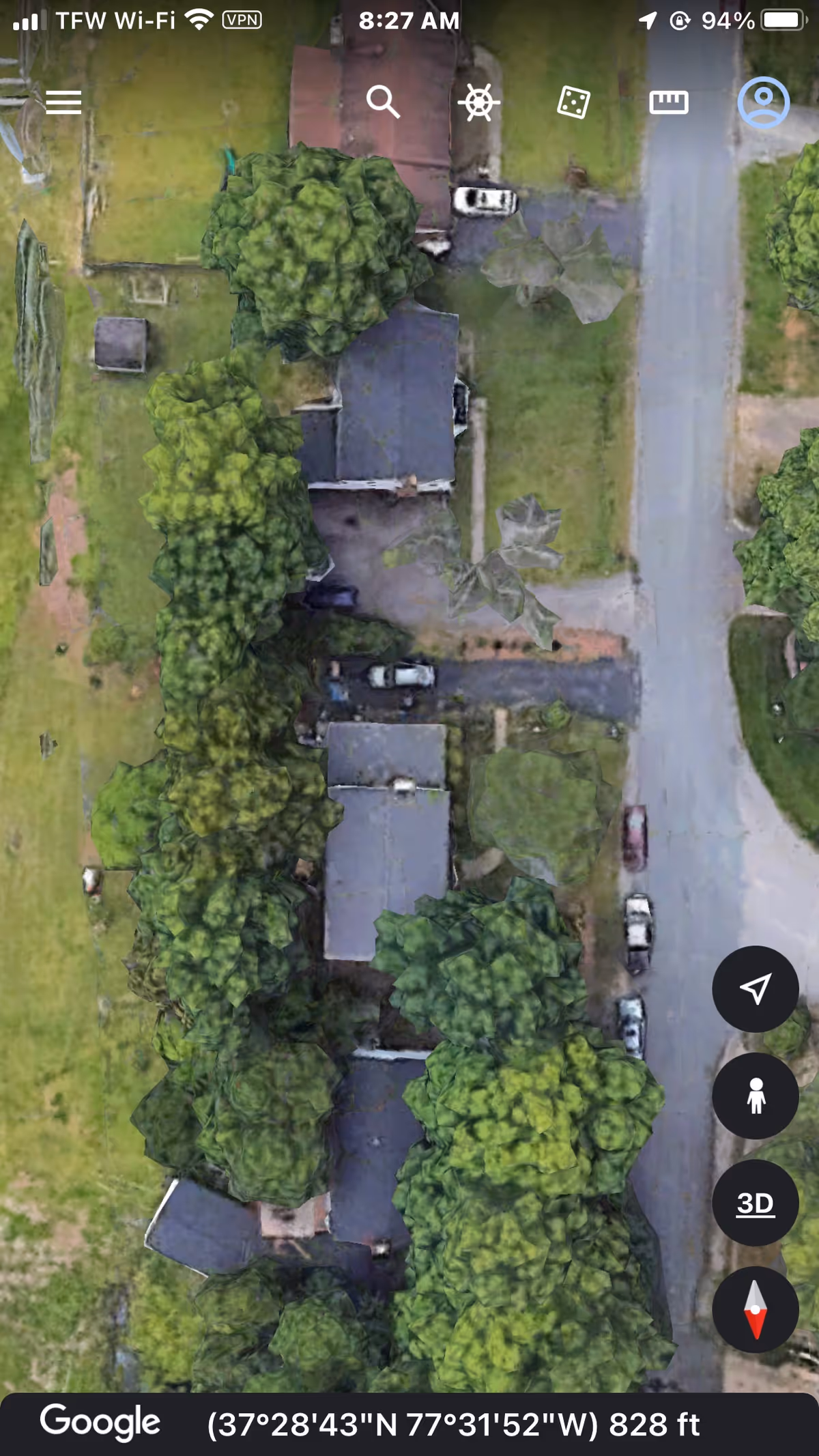 Aerial view of a tree-lined street with houses and green spaces.
