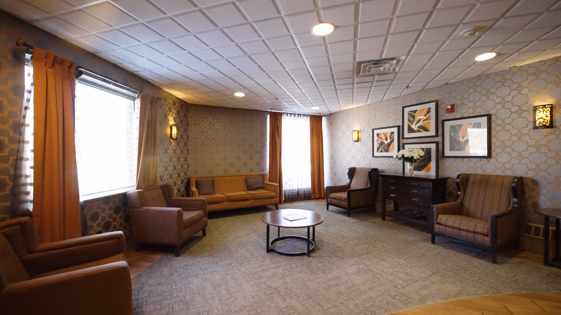 Senior living facility lounge with plush seating, coffee table, and wall art.