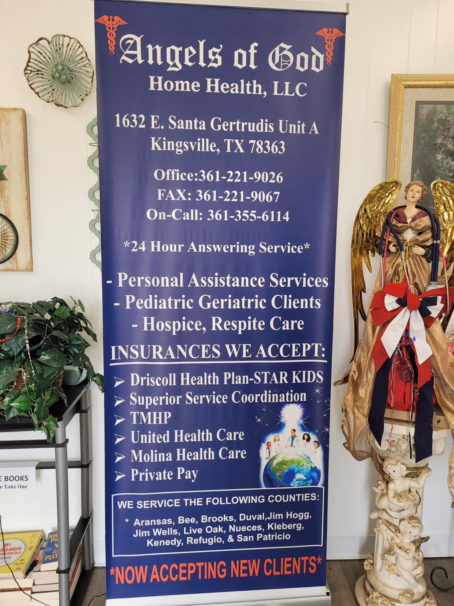 Inside a facility, a blue banner reads Angels of God Home Health, LLC beside a statue.