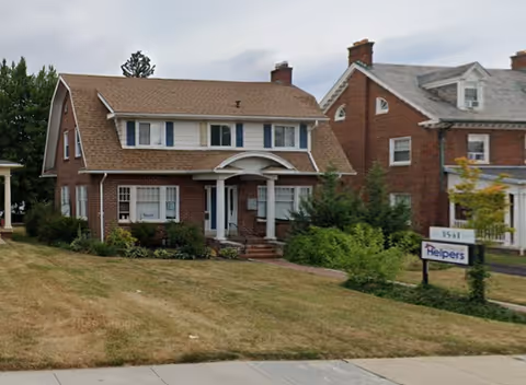 Brick two-story building with manicured lawn and a Senior Helpers sign in front