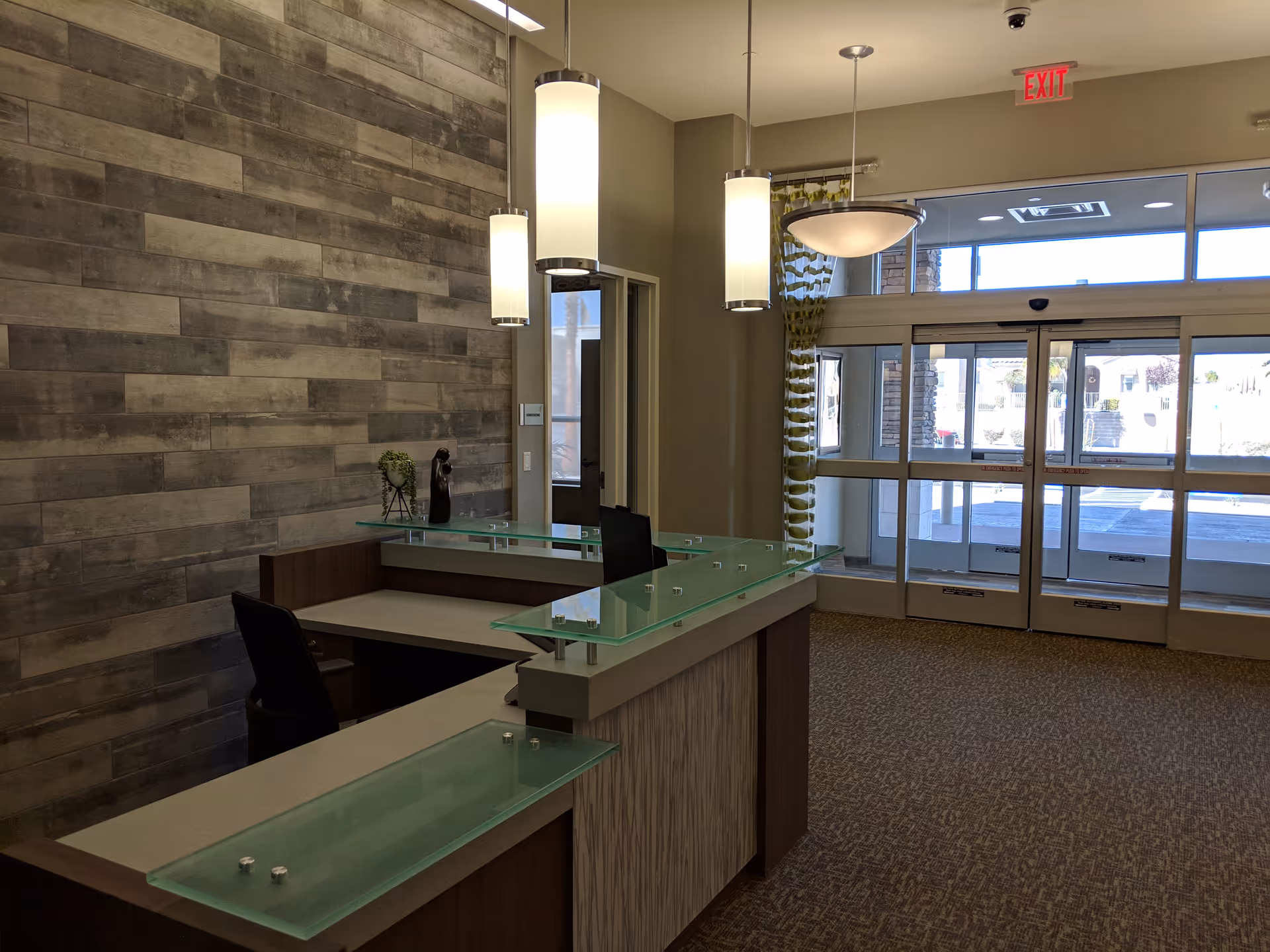 Reception desk in a modern lobby with glass panels and doors.