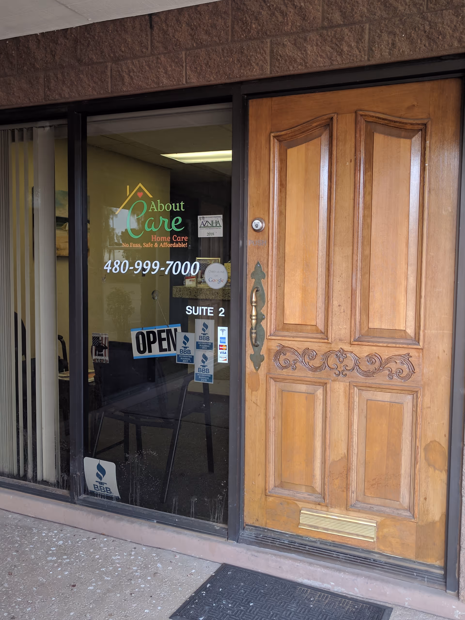 Exterior storefront with glass door, ornate wooden entry door, and About Care Home Care signage.