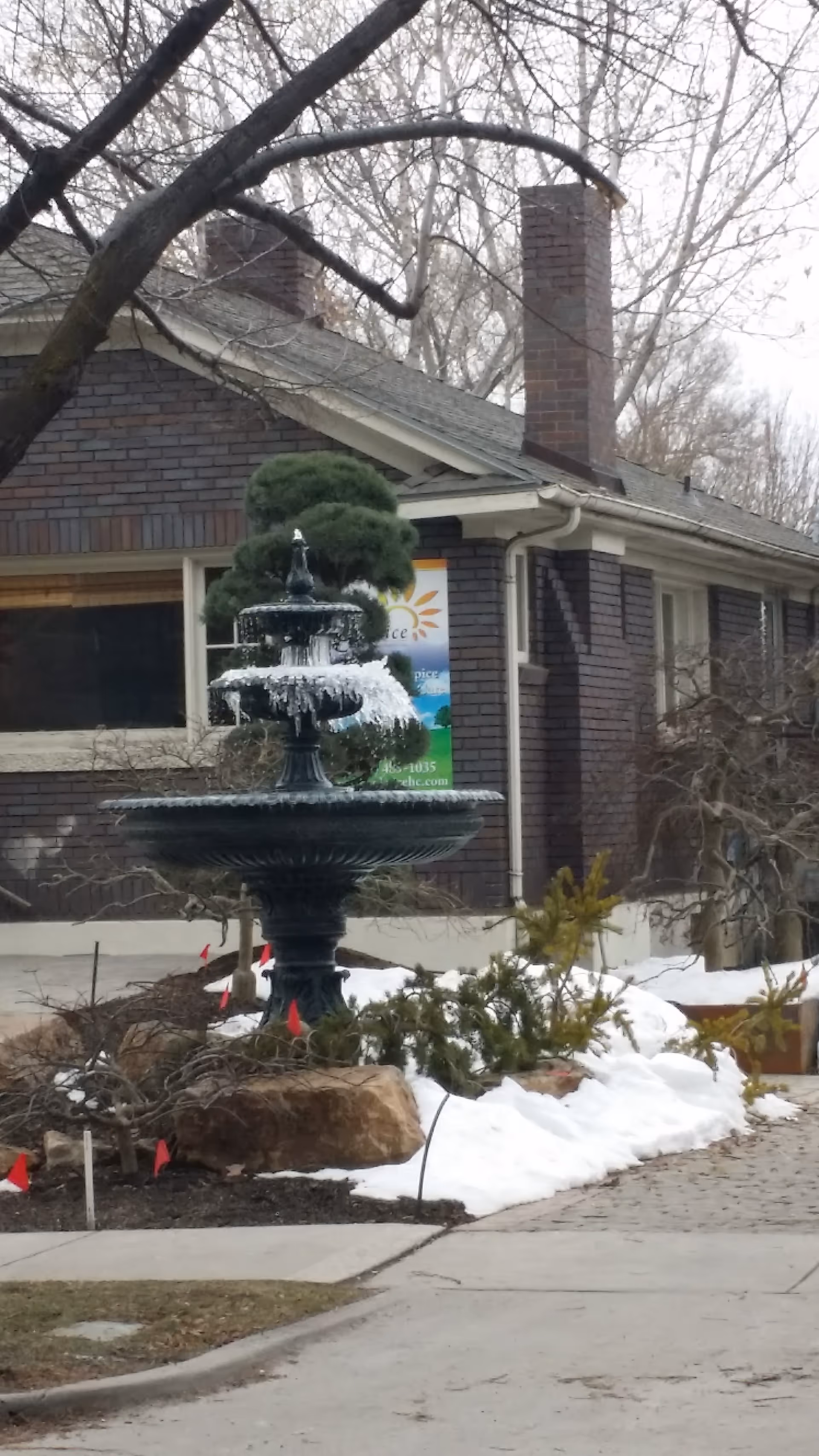 Brick building with a tiered fountain and snow near the entrance.