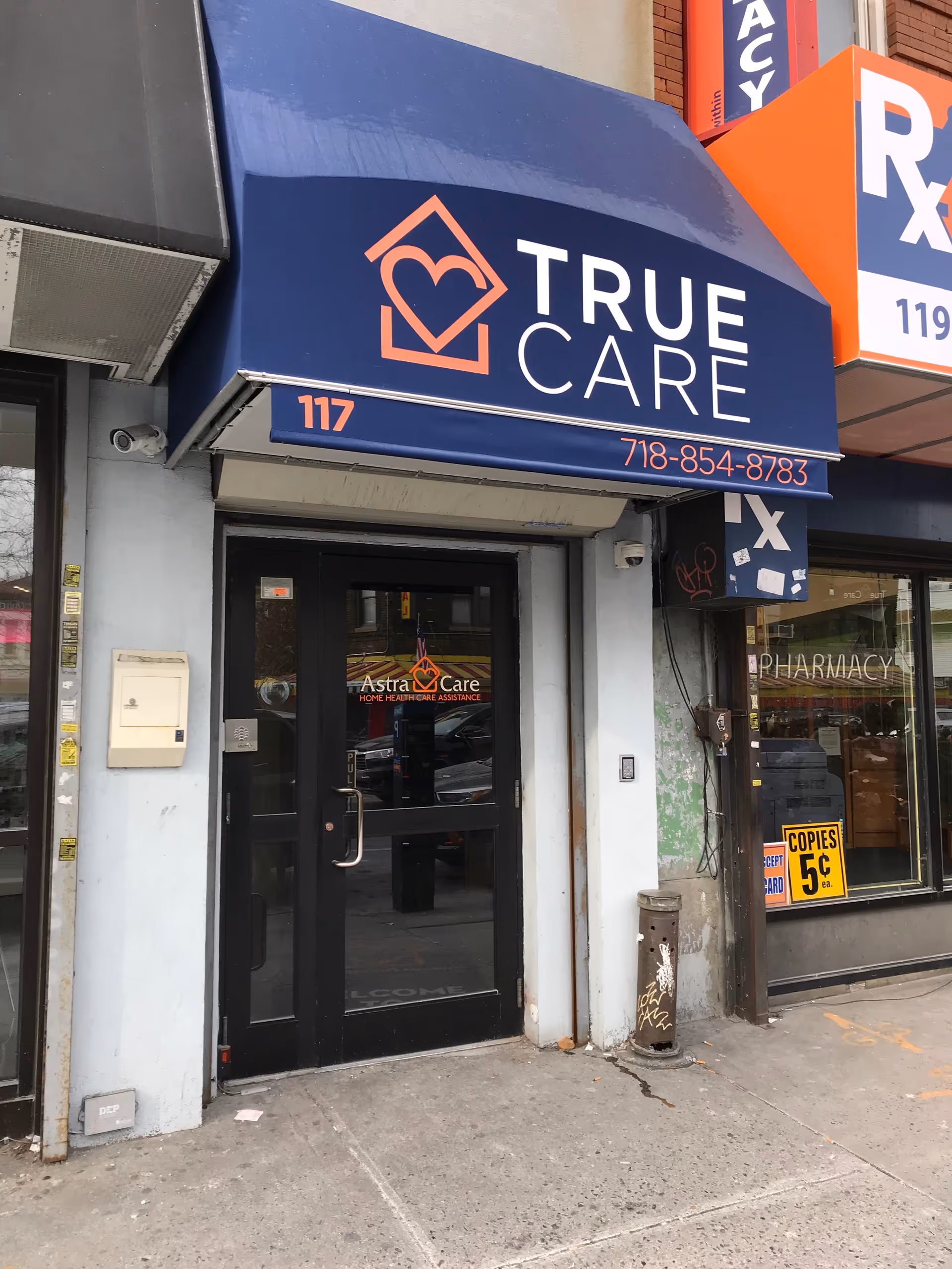 Blue awning with TRUE CARE logo above glass entrance storefront.