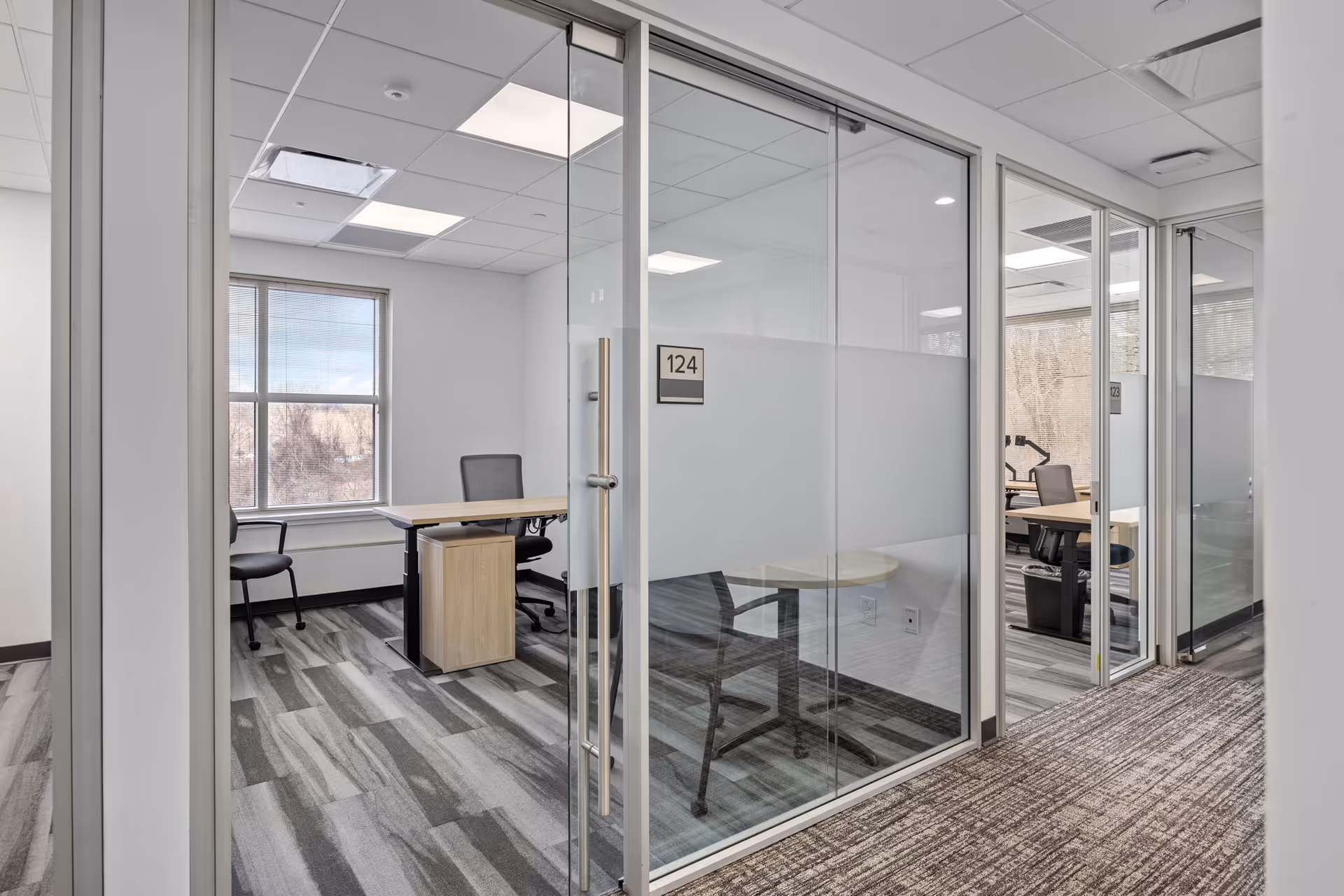 Glass-walled office area with desks and chairs in a senior facility.