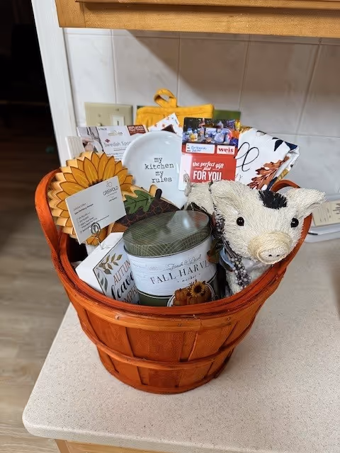 Orange wicker gift basket with fall decor sits on a kitchen counter.