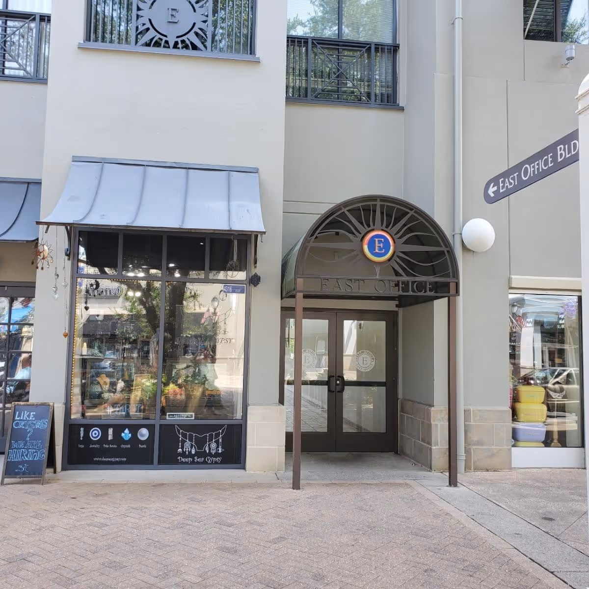 Exterior storefront with arched entrance labeled East Office and adjacent shopfronts.