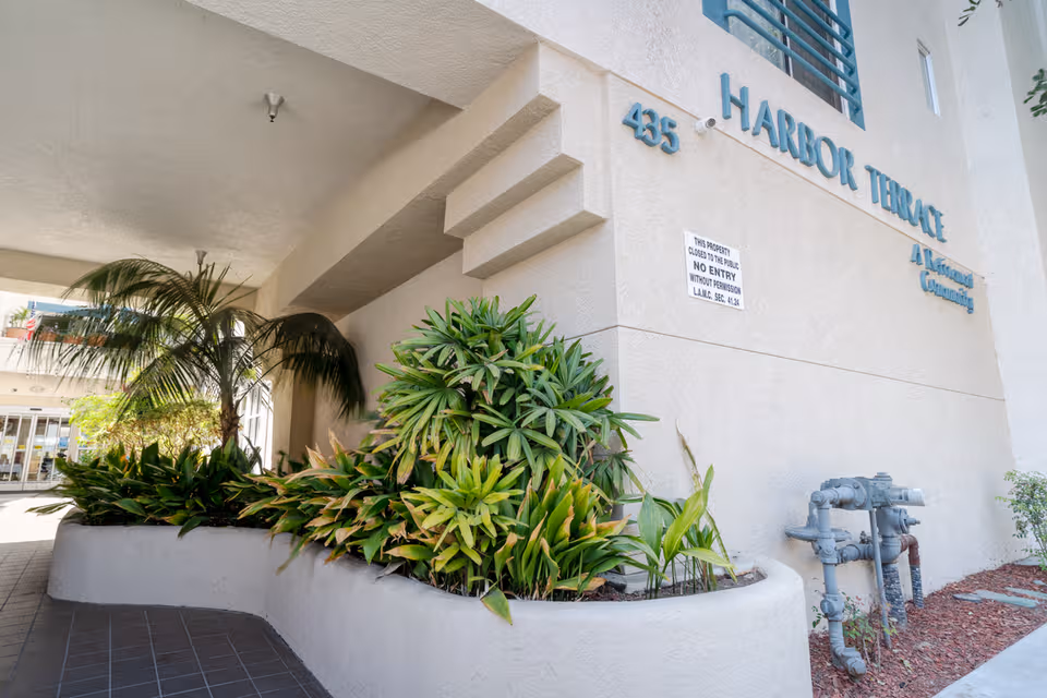 Front exterior of Harbor Terrace Retirement Community with lush landscaping