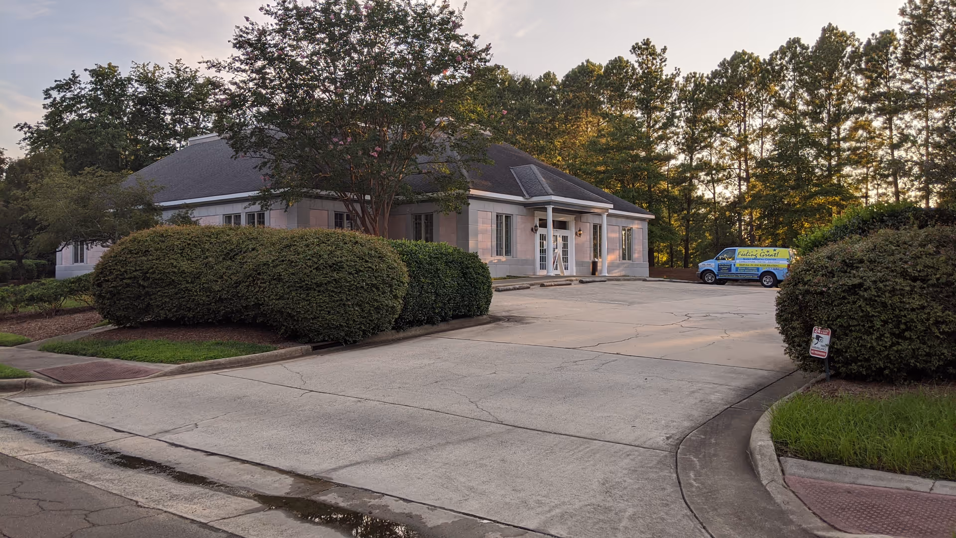 Front exterior of a single-story senior living facility with curved driveway and trimmed shrubs