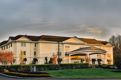 Two-story senior living facility with a curved entry canopy and well-kept landscaping