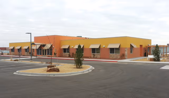 Colorful single-story senior living building with a circular driveway and parking lot.