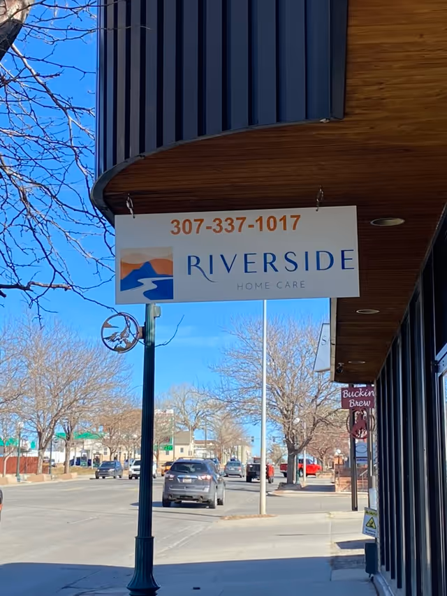 Exterior street view of Riverside Home Care - Casper sign on storefront with cars.