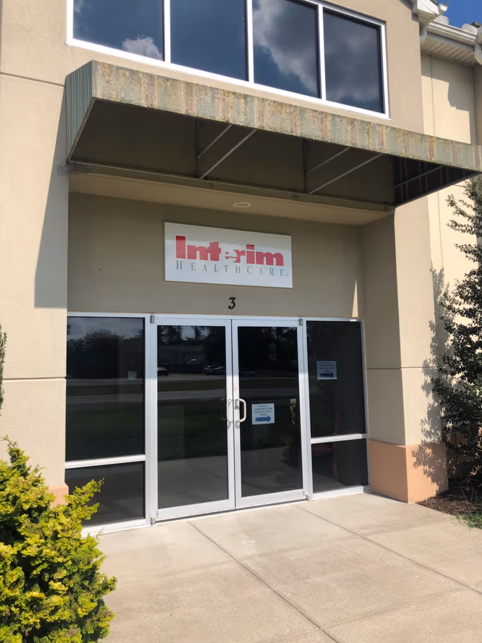 Front entrance of Interim HealthCare building with glass doors and a sign.