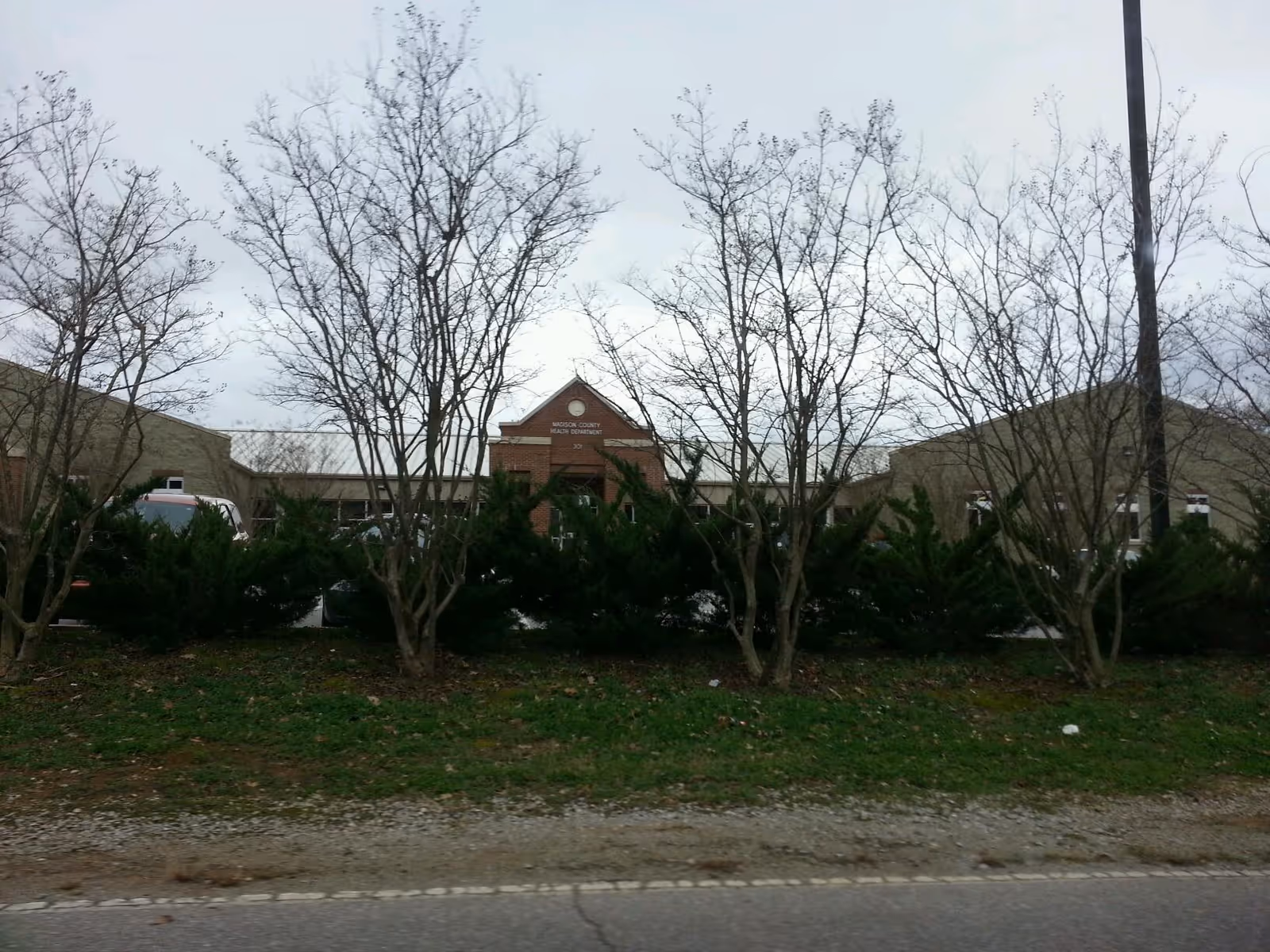 Exterior view of Madison County Health Department building behind bare trees.