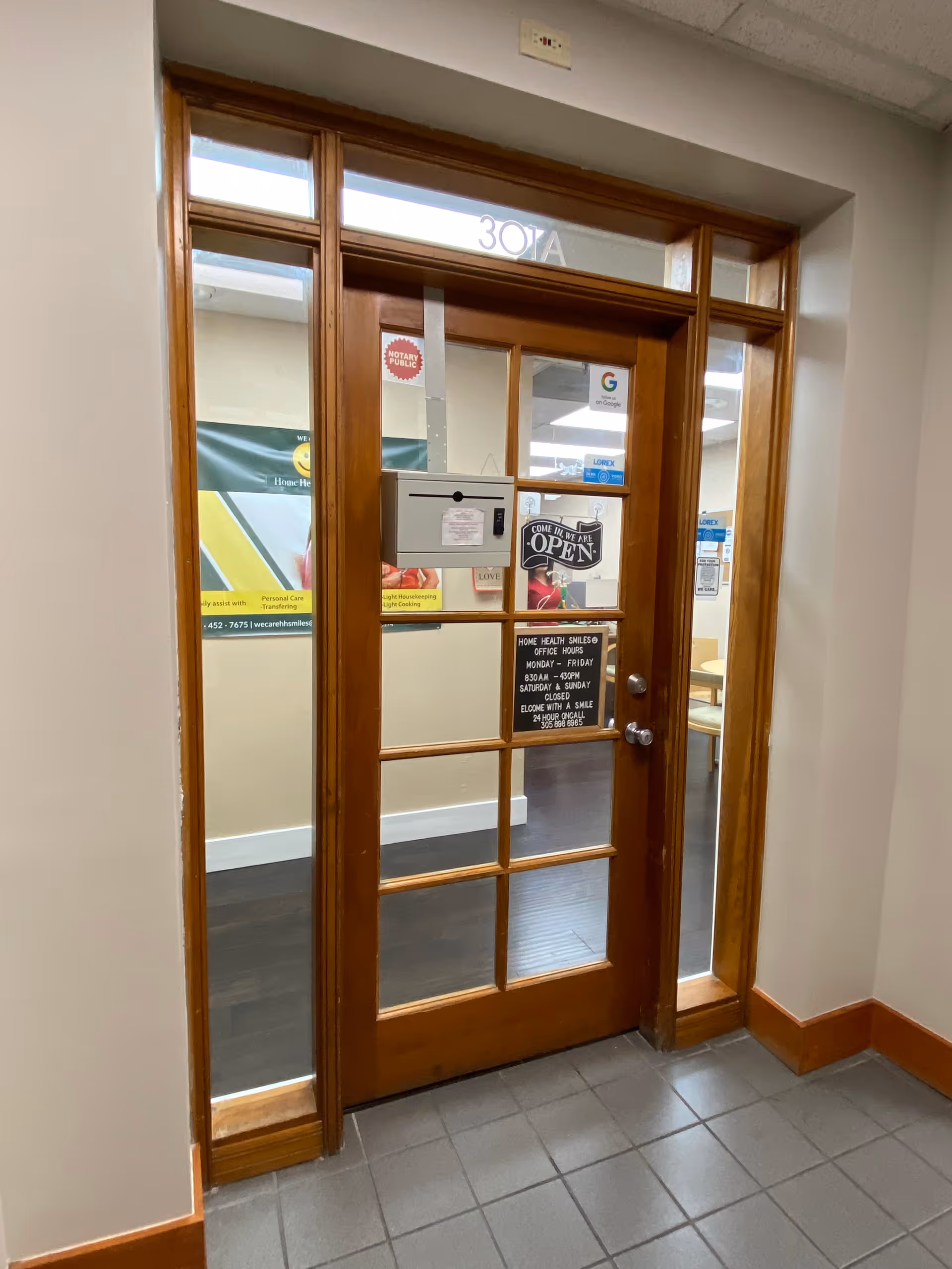 Wooden glass-paneled door opens into a hallway inside the facility.