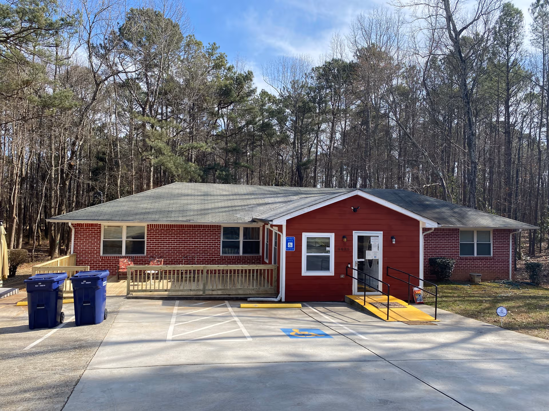 Front view of a red brick senior care home with wheelchair ramp and parking.