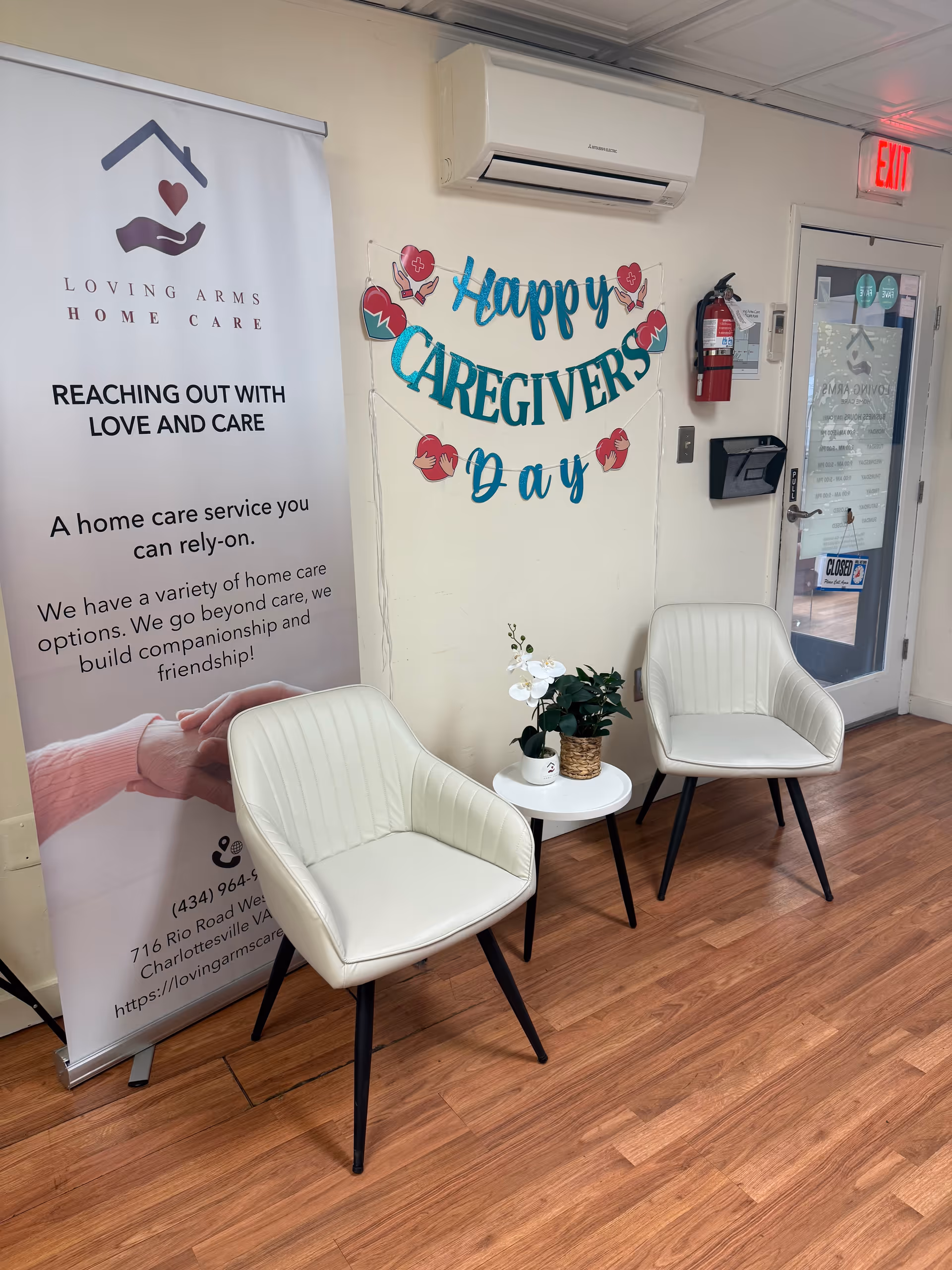 Two white chairs by a small table with a 'Happy Caregivers Day' banner nearby.