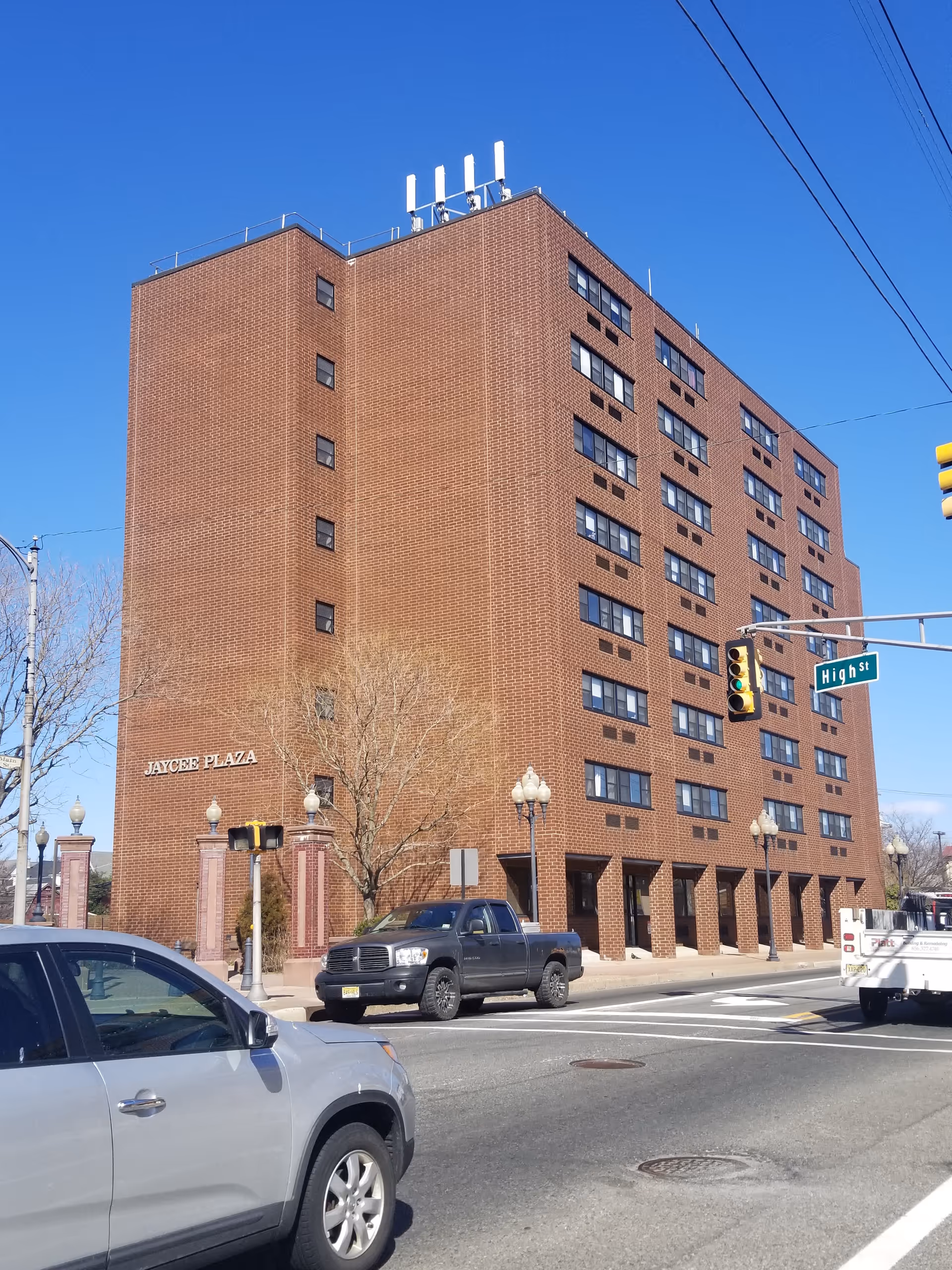 Tall brick assisted living building on a street corner with parked cars.