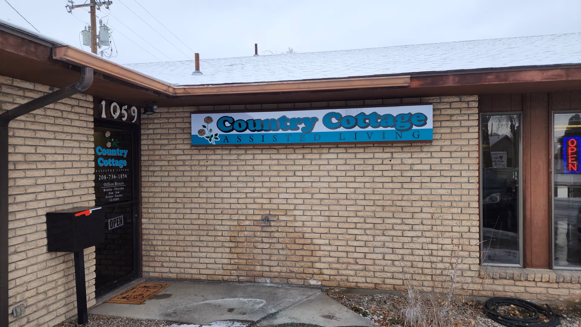 Brick exterior of Country Cottage Assisted Living with a blue sign above the doorway.