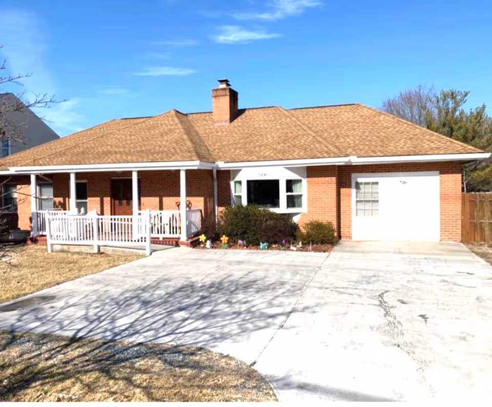 Brick, single-story building with a covered front porch and white railing.