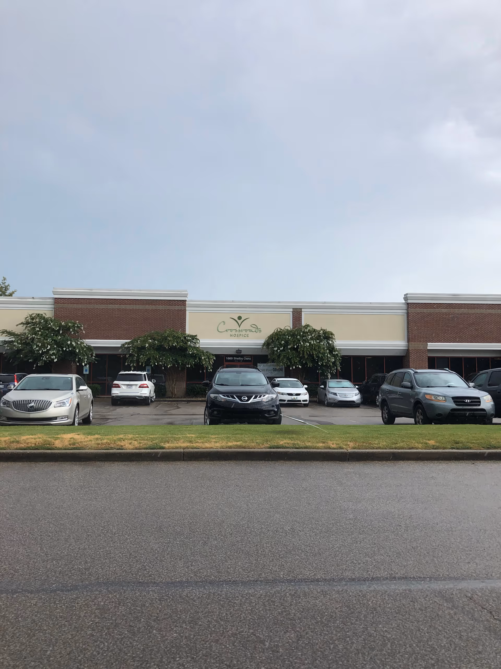 Facade of Crossroads Hospice & Palliative Care with parked cars in front.