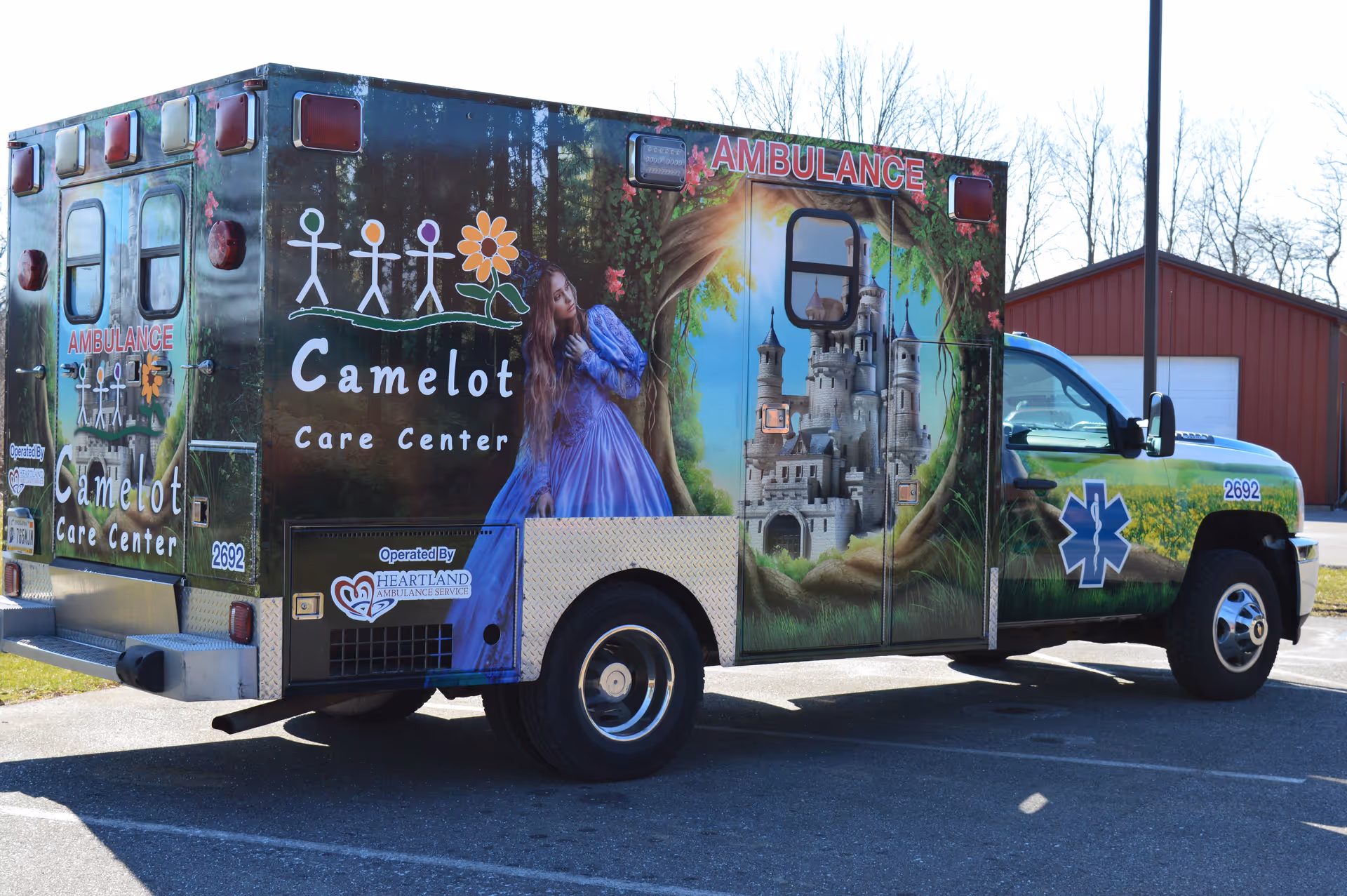 A Camelot Care Center ambulance decorated with a painted princess and castle parked outdoors.
