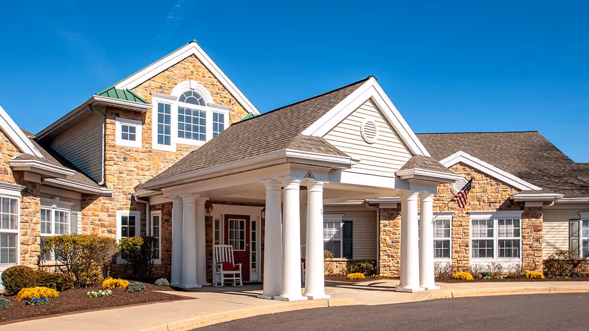 Front exterior view of a memory care facility with stone facade and white columns.