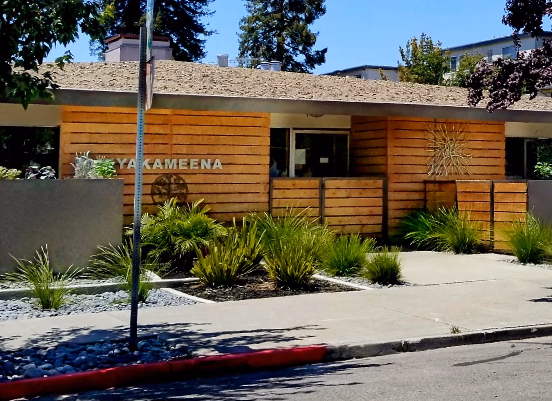 Exterior view of Kyakameena Care Center with wooden facade, landscaping, and a sidewalk.