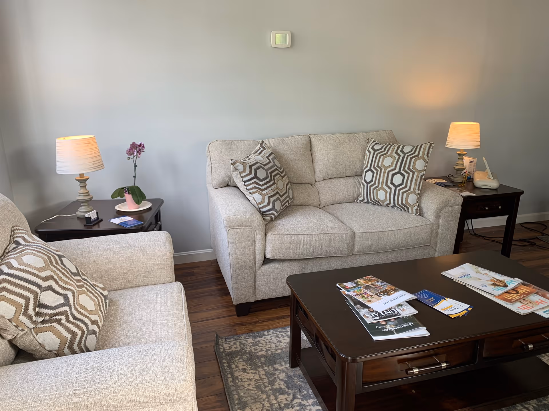 Cozy living room in a senior facility with beige sofas, side tables, lamps, and coffee table.