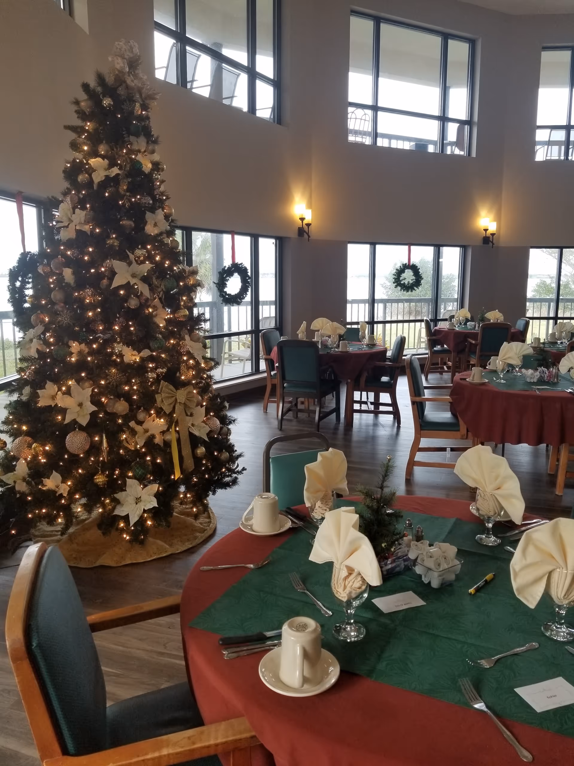 A festive dining room in a senior living facility with Christmas tree and tables.