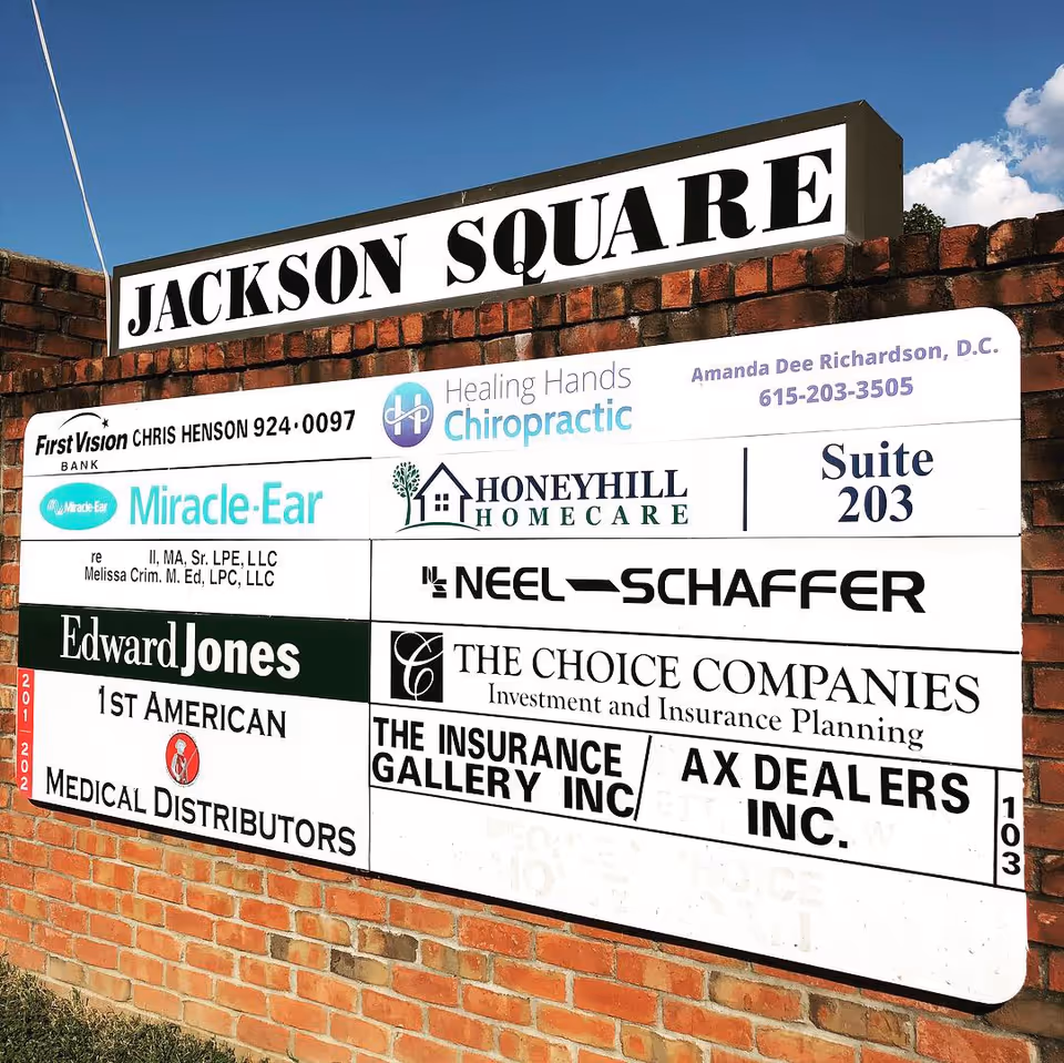 Exterior signboard on a brick wall displaying HoneyHill HomeCare among businesses.