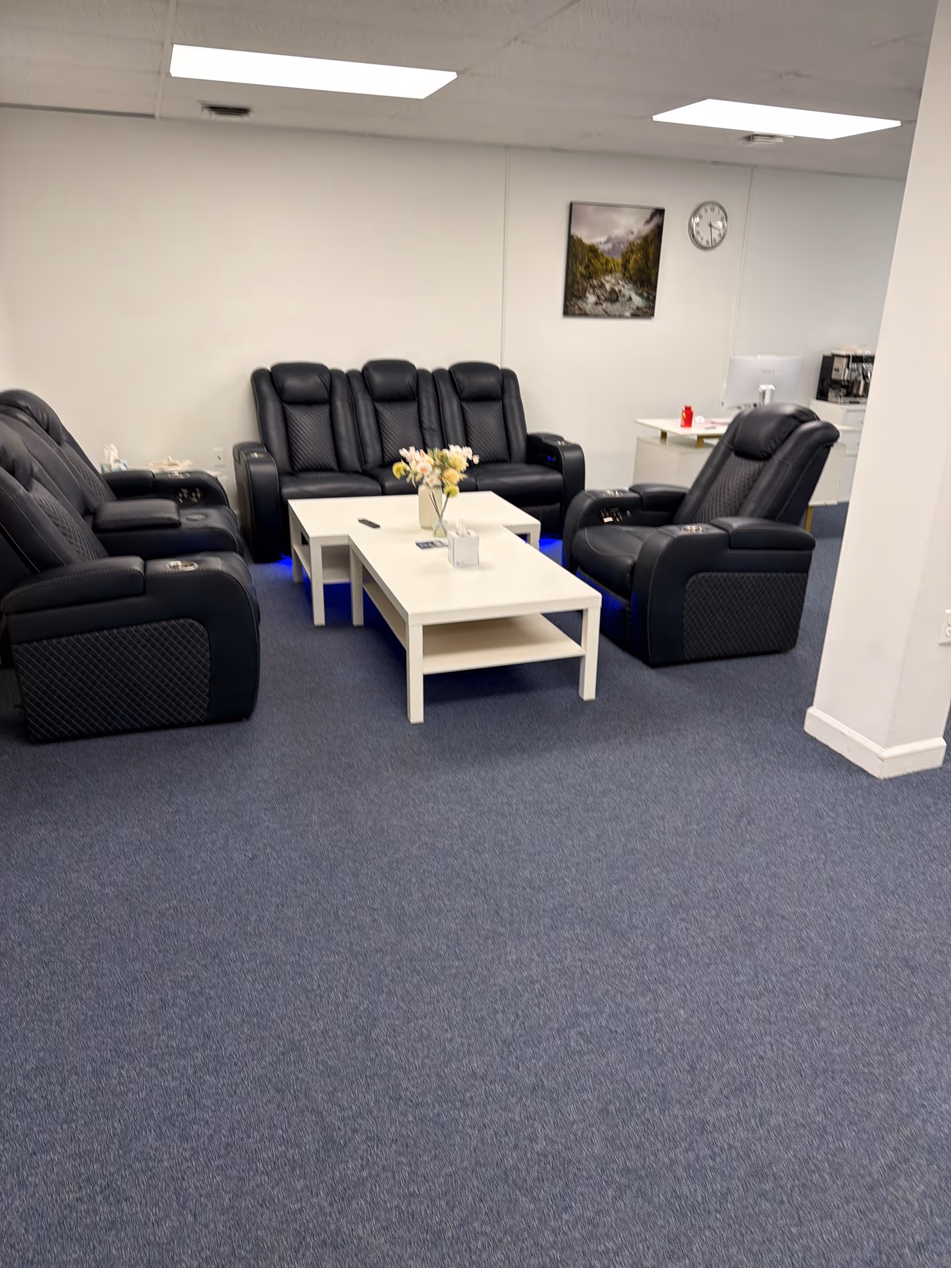 A lounge area with black leather recliners around a white coffee table.
