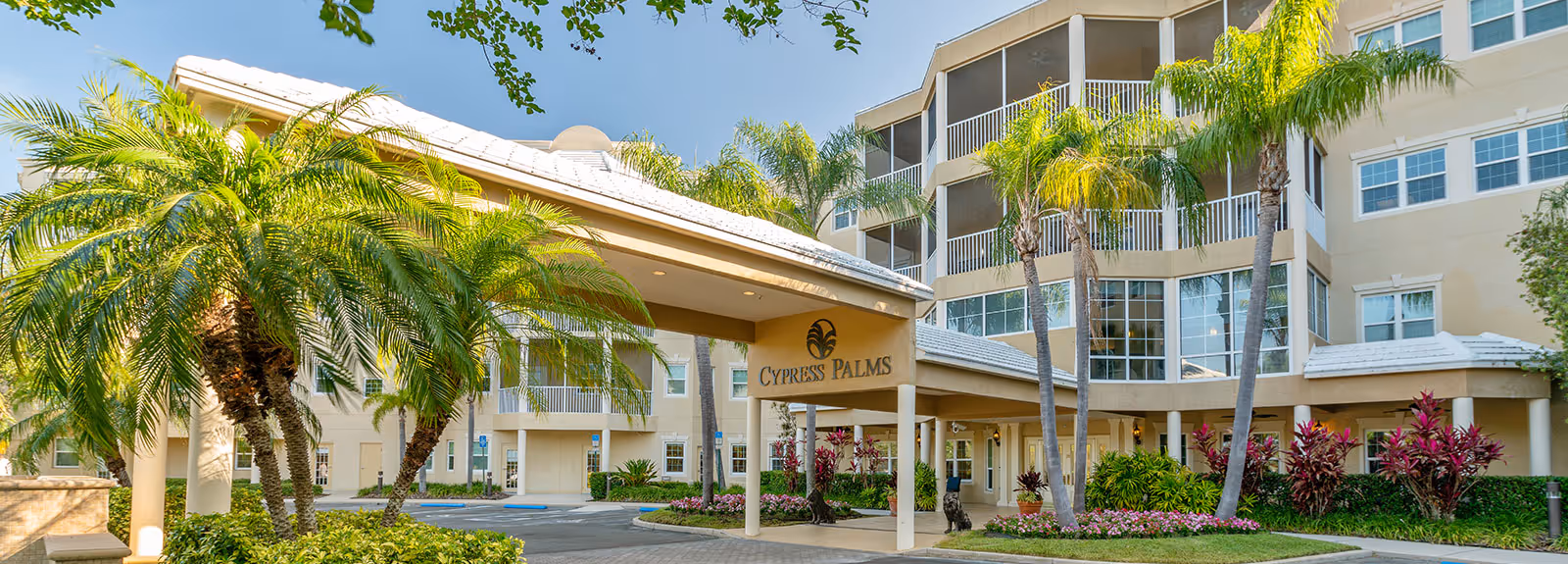 Exterior view of the Cypress Palms senior living facility with palm trees and landscaped gardens.