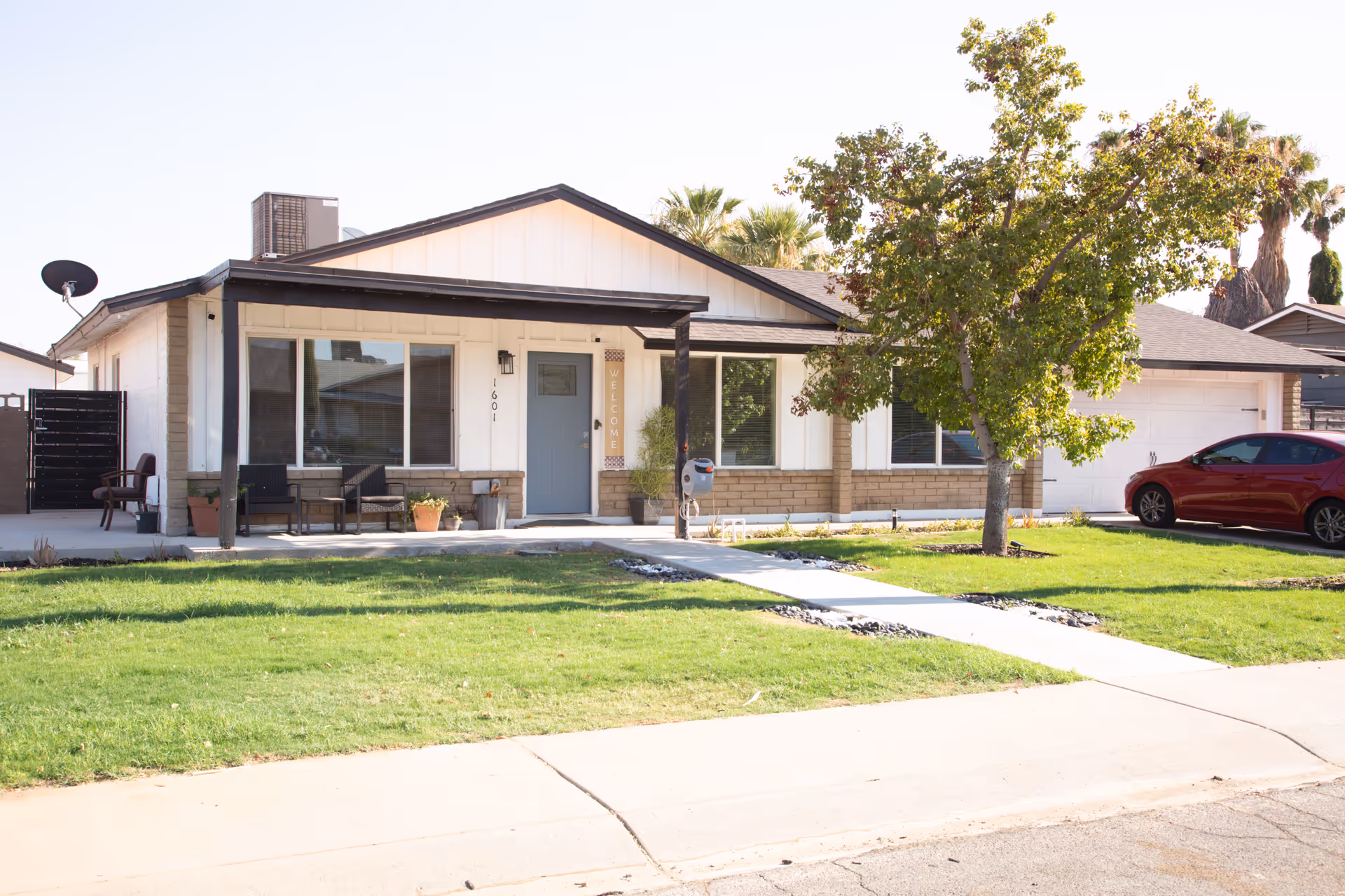 Front exterior of Caring Hand Assisted Living, a single-story home with lawn and a tree.