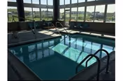Indoor pool area with metal handrails and large windows overlooking outdoors.