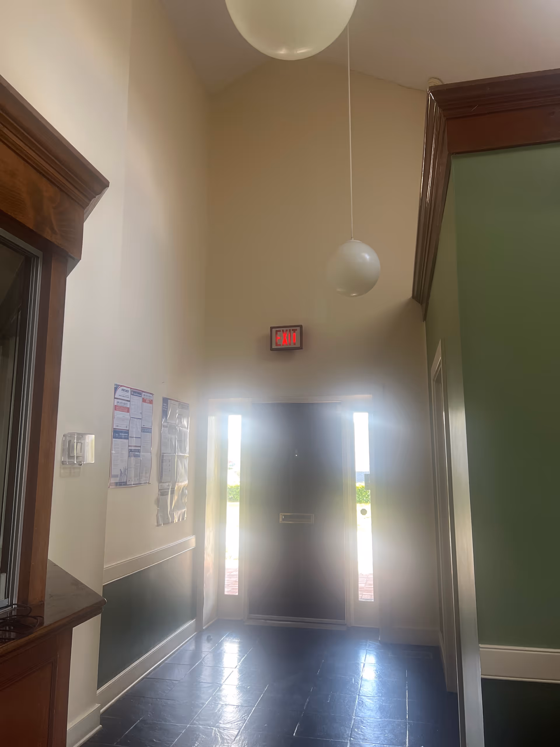 Interior hallway of a senior care facility with exit door and wall posters.