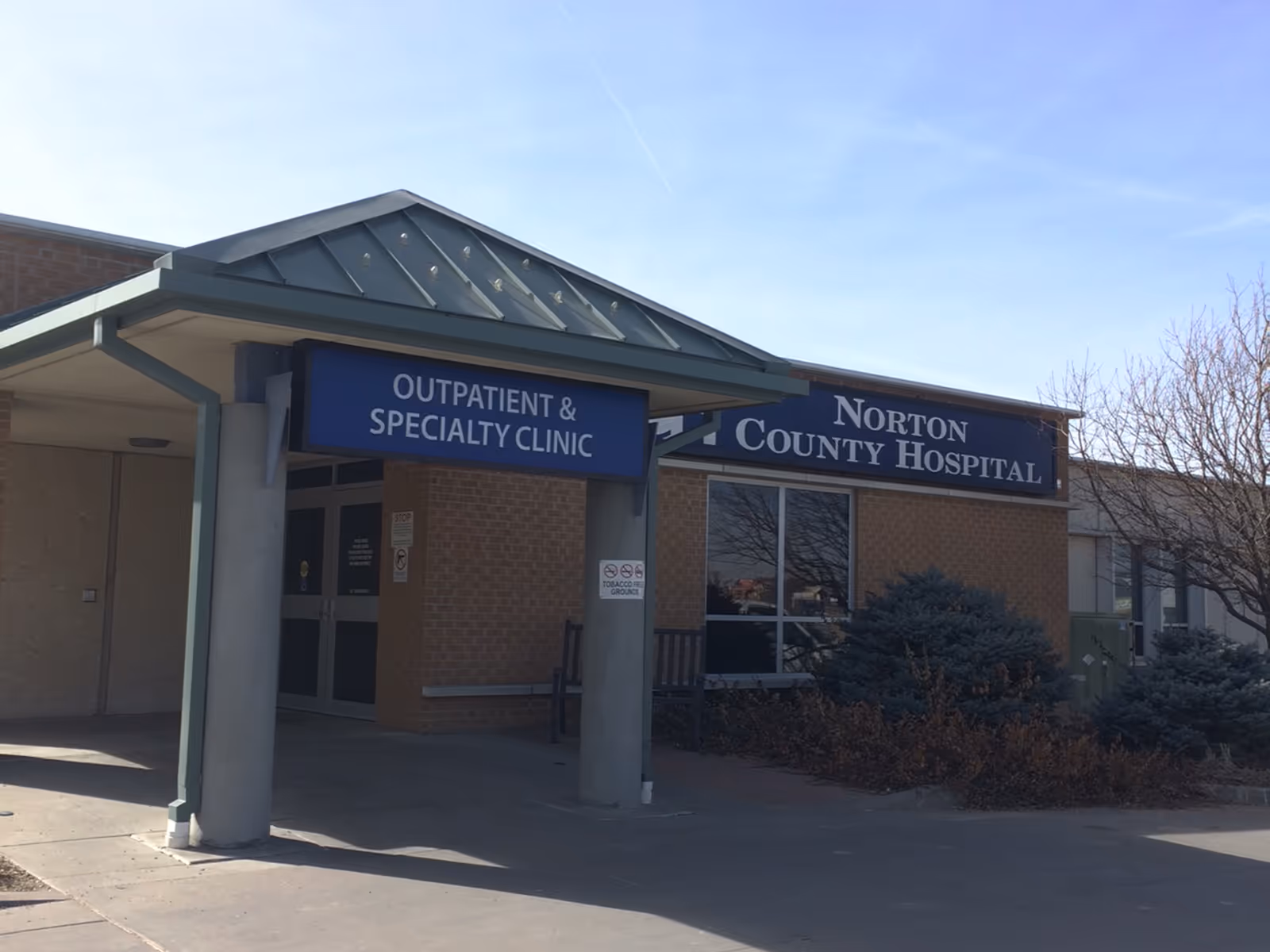 Front exterior of Norton County Hospital with blue signage reading Outpatient & Specialty Clinic at entrance