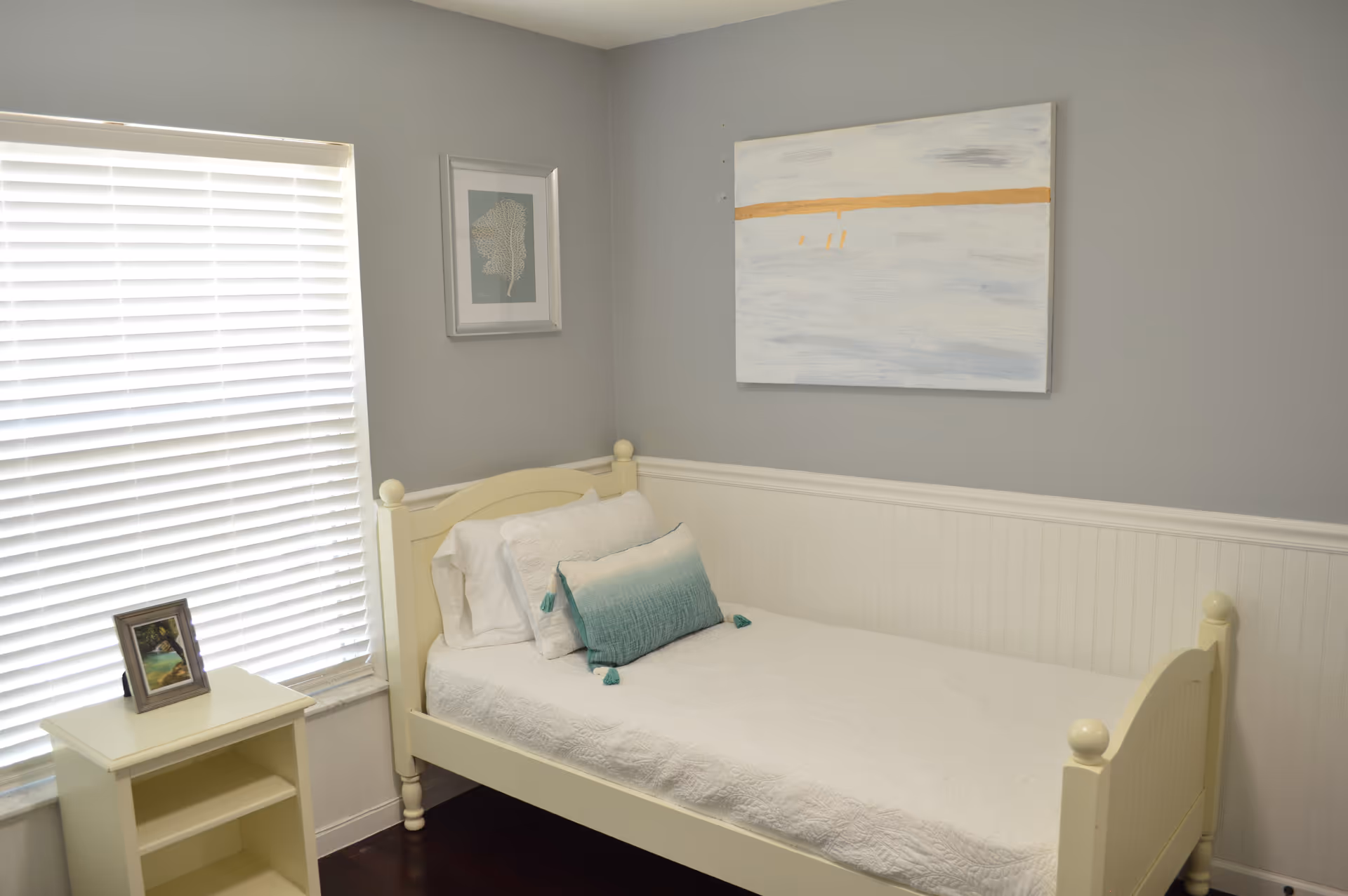 Small cream bedroom with single bed, nightstand, and window with blinds