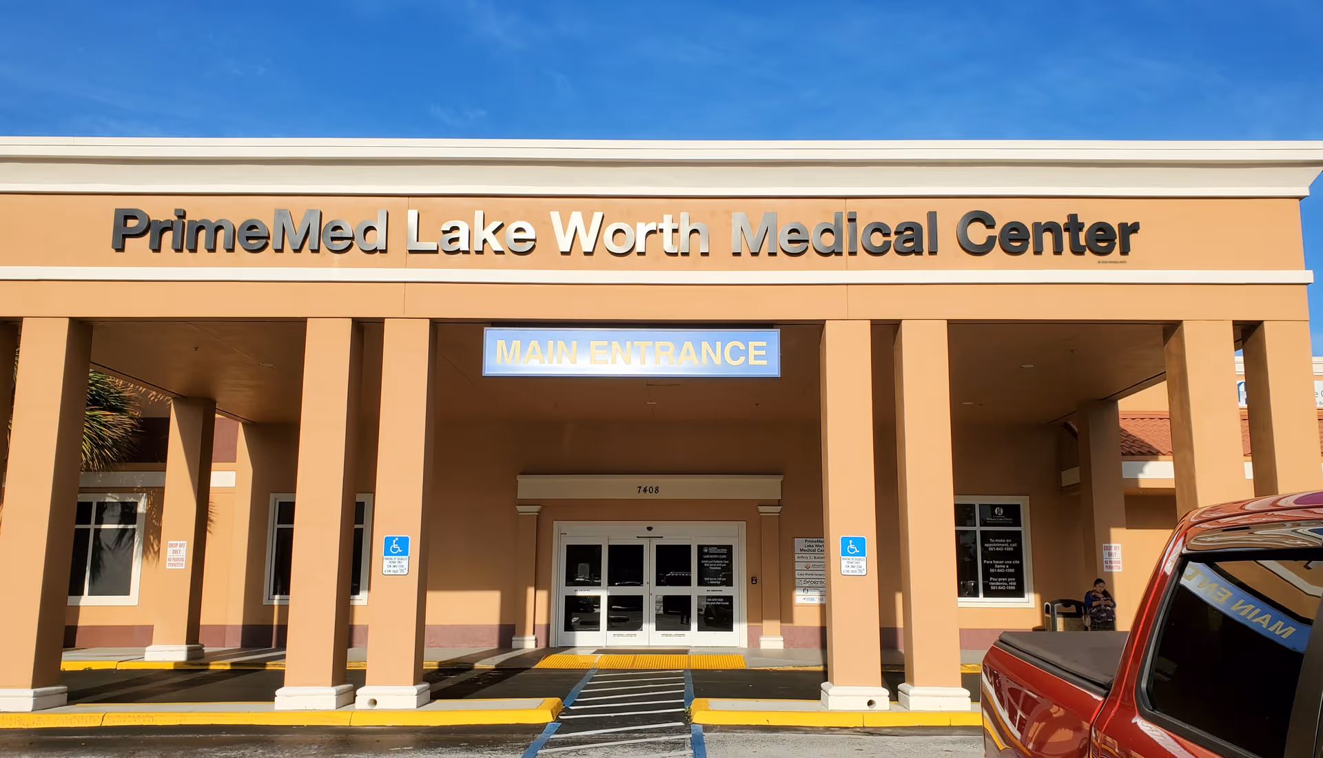 Front entrance of PrimeMed Lake Worth Medical Center with a main entrance sign.