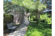 Outdoor walkway at Candlewood Valley Health and Rehabilitation Center with a bench under trees.